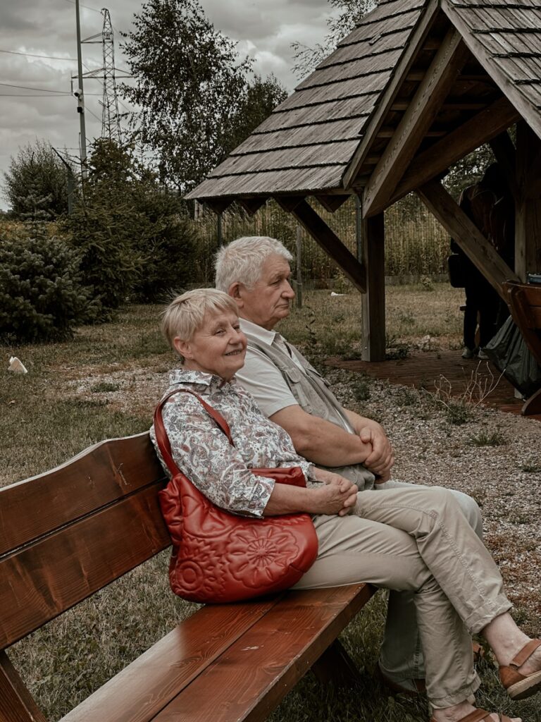 a man and a woman sitting on a wooden bench